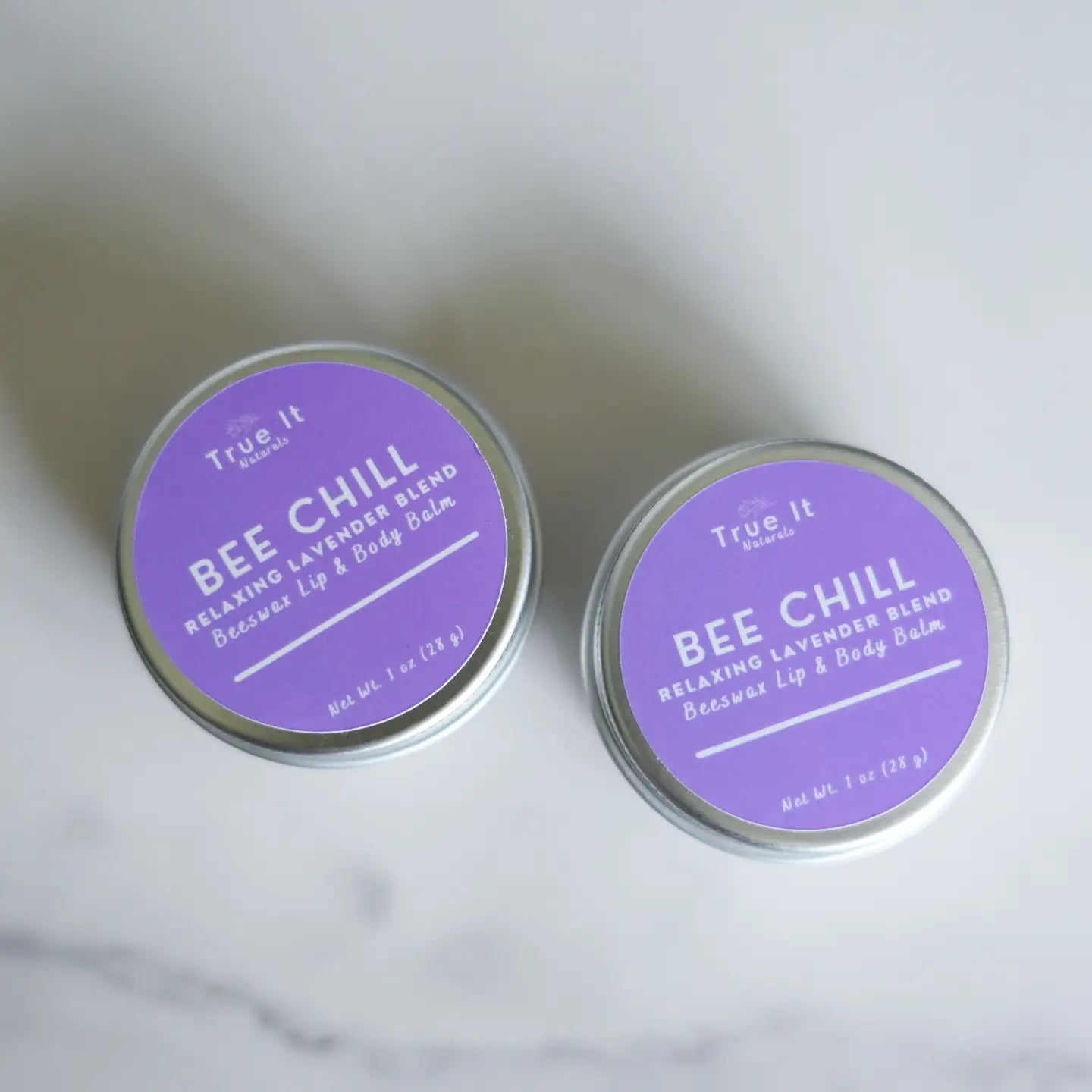 Two tins of True It Naturals Bee Chill Beeswax Lip Balm on a white background