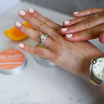 Load image into Gallery viewer, Close-up of two hands rubbing in some of the beeswax balm with blurred background
