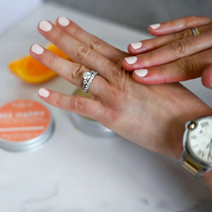 Close-up of two hands rubbing in some of the beeswax balm with blurred background