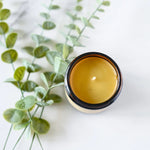 Load image into Gallery viewer, Jar of True It Naturals beeswax candle next to sage leaves on a white background
