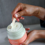 Person using a wooden applicator to scoop body butter from a jar of Large (4oz) True It Naturals Citrus Cream Body Butter