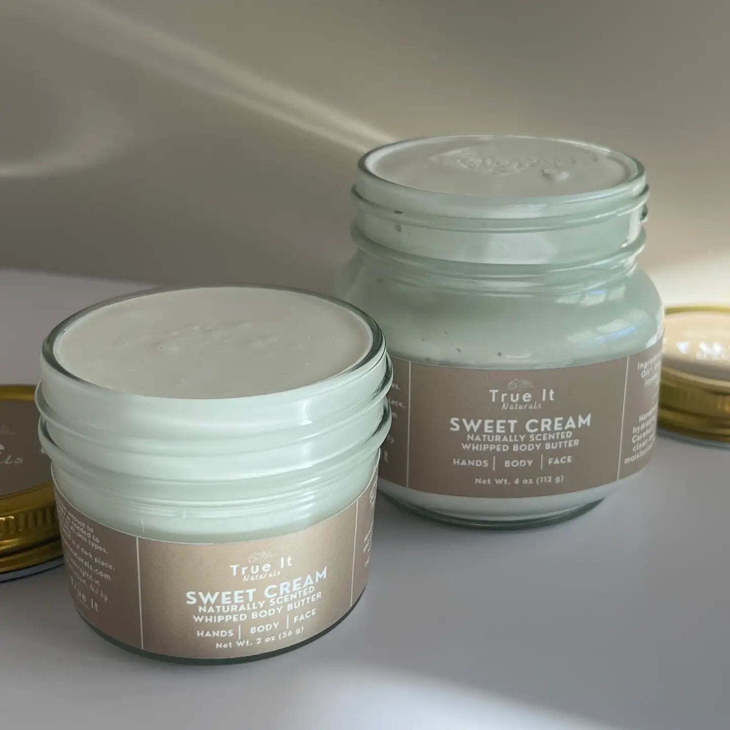 Large (4oz) and Small (2oz) Sweet Cream Body Butters with the lids off featuring the cream texture.