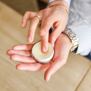 Person applying Beeswax lip balm from a small container of True It Naturals.