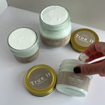 Jars of Small (2oz) and Large (4oz) True It Naturals Sweet Cream with the lids off showing the cream texture. Also someone scooping some cream out of a jar with a finger.